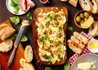 Homemade trendy butter board with onion, olives, herbs and bread. Butter board with toasts on dark...