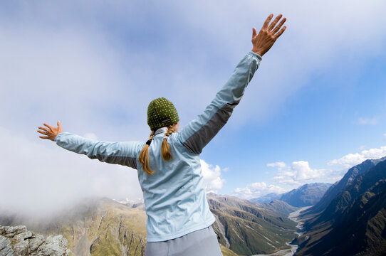 On the fourth day of the Three Passes Track a female backpacker is spreading her arms on top of Browning Pass. New Zealand.
