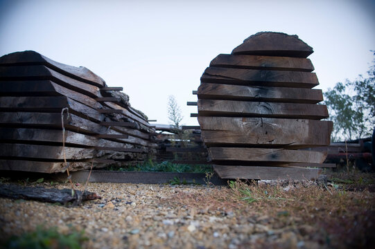 Stacks of rough cut lumber sit with stickers separating the boards in the yard of a woodshop in Deforest, WI.