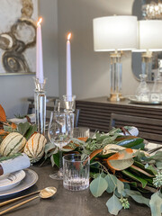 Autumn table setting with fresh pumpkins and flowers in room, Thanksgiving concept
