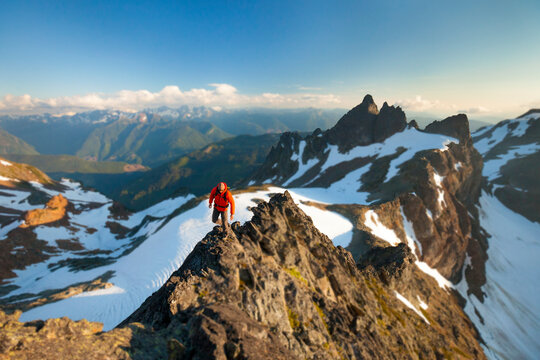 Selective focus on a climber walking an exposed section of rocky mountin ridge.