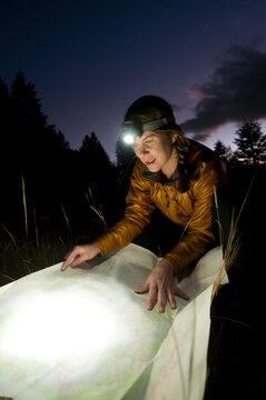 A young woman reads a topographic map while hiking in Grand Teton National Park, Jackson Hole, Wyoming.