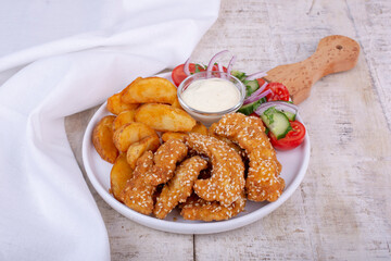 Delicious chicken breast strips, crispy, fried and breaded, served with potato, fresh salad and sauce.