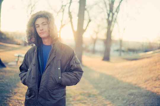 Portrait of a young man wearing a winter jacket in the park at dusk.