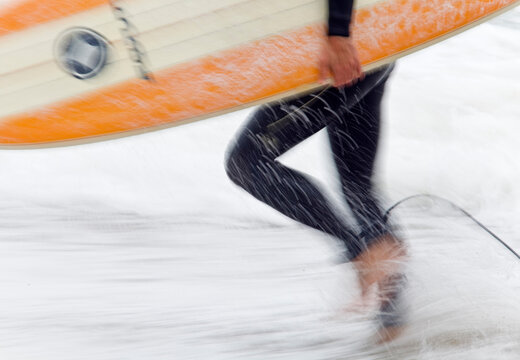 Close up of a Surfer carrying colourful surf board from the beach,Cornwall,UK