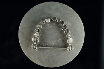 Close-up studio shot on milled metal frame for dental implants on the black background. Concept of new technologies in dental prosthetics
