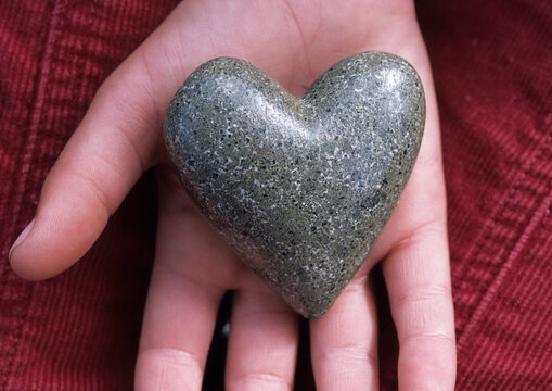 Rock shaped heart on open hand.