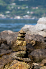 light brown and gray stones stacked on top of each other with the blue water of the fjord and the rocky coast in the background