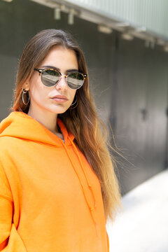 City portrait of positive young female wearing casual clothes orange. Grey background