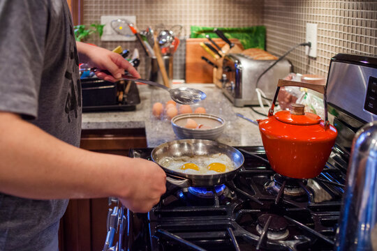 close-up view of a man's hands cooking breakfast at the kitchen stove