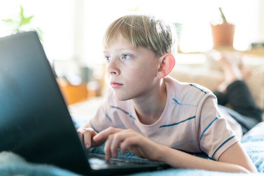 Close up portrait of teen working on laptop inside on bright sunny day