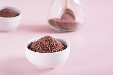Black himalayan salt of medium grinding in a bowl on a pink background