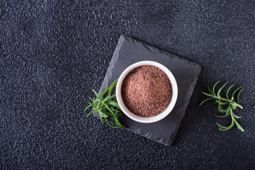 Black Himalayan kala namak salt in a bowl and rosemary on a black background. Top view.