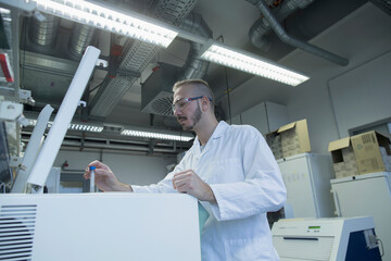 Young male scientist examining test tube in a pharmacy laboratory, Freiburg im Breisgau, Baden-Württemberg, Germany