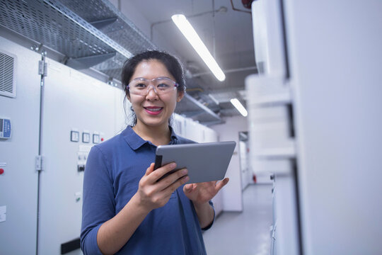 Young female engineer updating control panel using digital tablet in an industrial plant, Freiburg im Breisgau, Baden-Württemberg, Germany