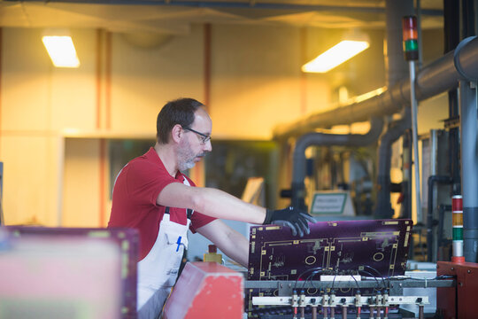 Male engineer examining circuit board in industry, Hanover, Lower Saxony, Germany