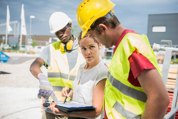 Architect reviewing blueprint with construction workers at building site