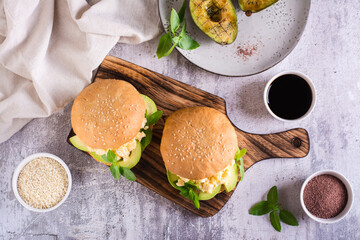Delicious sandwich with scrambled eggs, avocado and basil on a board. Healthy food. Top view