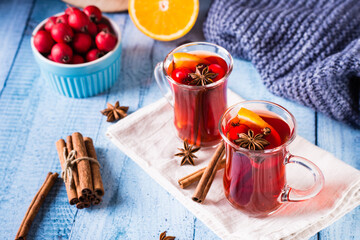 Homemade hot mulled wine with orange, cinnamon and berries in glasses on the table.