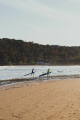 Wide Shot Of Two Female Surfers Getting Out Of The Water