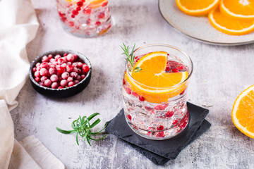 Hard seltzer cocktail with berries, orange, rosemary and ice in glasses on the table
