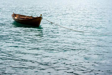 Naklejka premium blue fabulously beautiful water with small waves where there is a brown wooden boat tied with a small rope