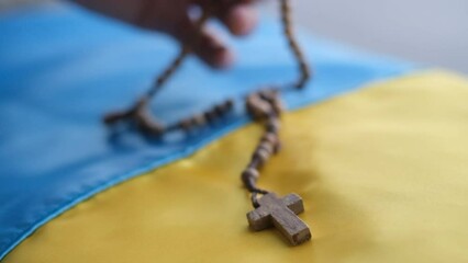 Christian cross on the Ukrainian flag. Religion concept. Prayer for peace in Ukraine on a rosary