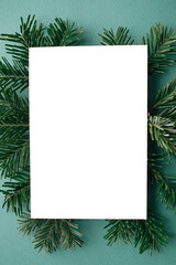 Fototapeta na wymiar Christmas card mock up. Modern greeting card flat lay with green fir branches on green background. Empty postcard template with space for text. Merry Christmas and Happy Holidays!
