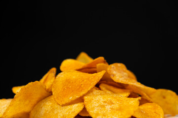 Delicious crispy potato chips with spices on a black background, place for text