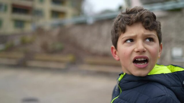 One upset preteen child turning head with concerned emotion. Tracking shot of young male kid feeling distress. Real authentic worried surprise expression