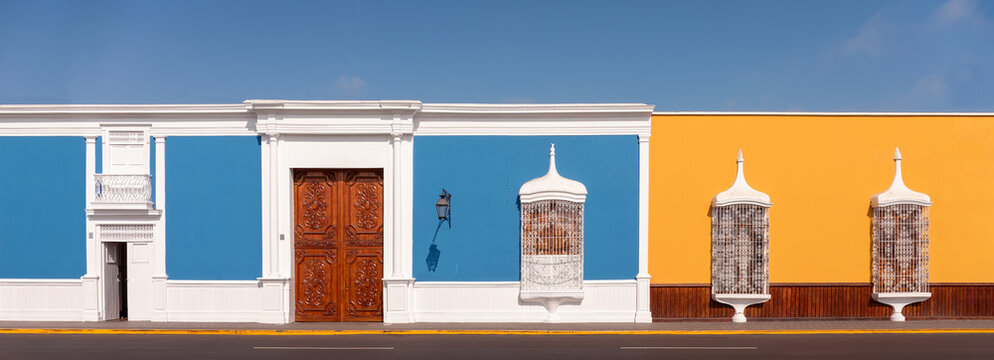 Traditional colonial architecture with white painted, delicate window railings, inlaid wooden doors and pastel colored walls, Trujillo, Peru