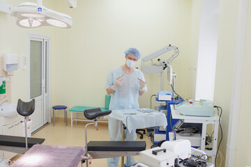 A male doctor taking a surgical instrument for a group of surgeons in the background in the surgery room. Steel medical instruments, ready to use. The concept of surgery and emergency care.