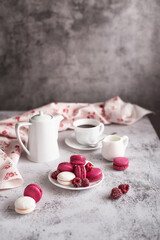 Sweet still life: macaroons with raspberries and a coffee service on a light marble table. Greeting concept for mother's day, international women's day or good morning wishes. Selective focus. 