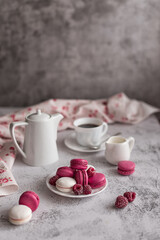 Fototapeta na wymiar Sweet still life: macaroons with raspberries and a coffee service on a light marble table. Greeting concept for mother's day, international women's day or good morning wishes. Selective focus. 