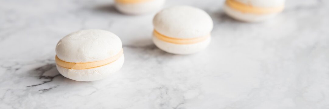Cake macaron or macaroon on marble background from above, white almond cookies, pastel colors, vintage card, top view.advertisement, copy space. web banner