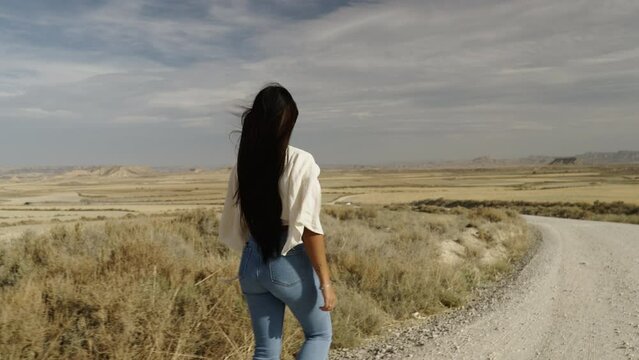 Latin girl with beautiful hair walks along a secondary road in Spain