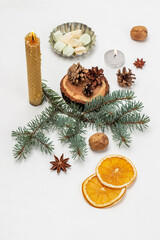 Cones on a stump, spruce branches and burning candles. Slices of dry oranges.