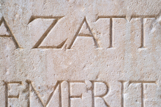 Old carved inscription letters in a light coloured stone surface.