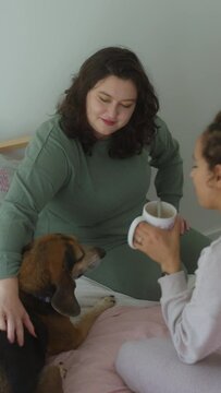 Lesbian couple with dog relaxing in bedroom
