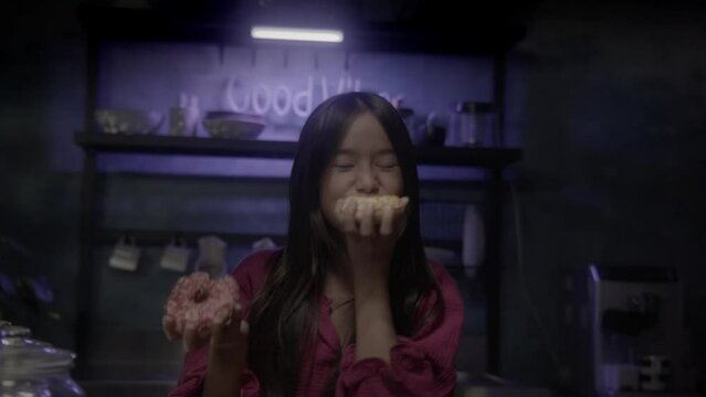 Young asian Girl in kitchen eating donuts