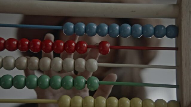 Young asian girl using a wooden abacus and calculator doing mathematics