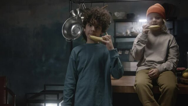 Two young boys hanging out in the kitchen talking on banana phone together