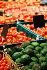 Fresh colourful vegetables: green avocado and red cherry tomatoes in boxes at market