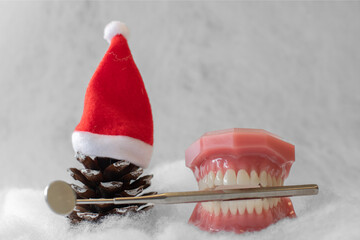 Zahn&auml;rztlicher Weihnachtshintergrund mit Platzhalter. Zahnmodell mit Weihnachtsm&uuml;tze und Weihnachtskugel