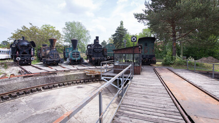 Several old trains and steam locomotives parked and stored on a siding at a railway turntable at a train station © Photofex
