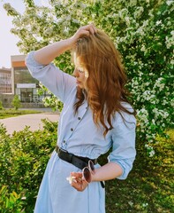  the girl holds her hair and flaunts near the apple tree