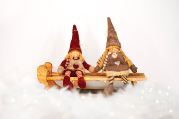 Christmas toys - girl and boy gnomes sitting on a sledge on snowy white background