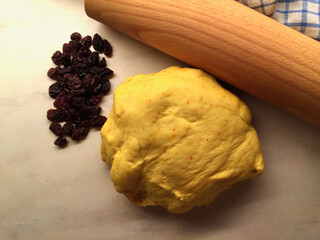 Saffron dough and raisins on a baking table for baking buns for December holidays.