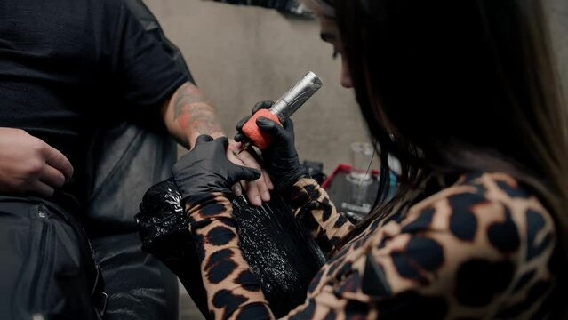 Close-up - a needle penetrates the skin, tattoo, tattoo studio