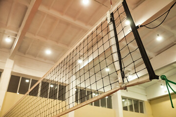Net of volleyball court in old school gym, bottom view. Background sports image of volleyball net...